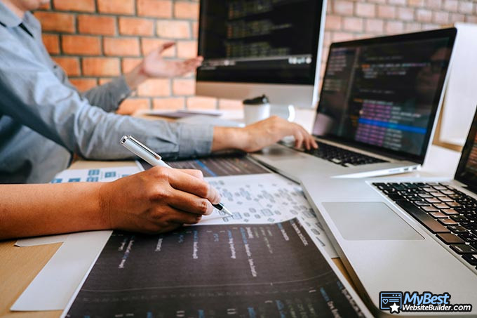 Cómo ser un desarrollador web: dos personas discutiendo código en dos computadoras diferentes.